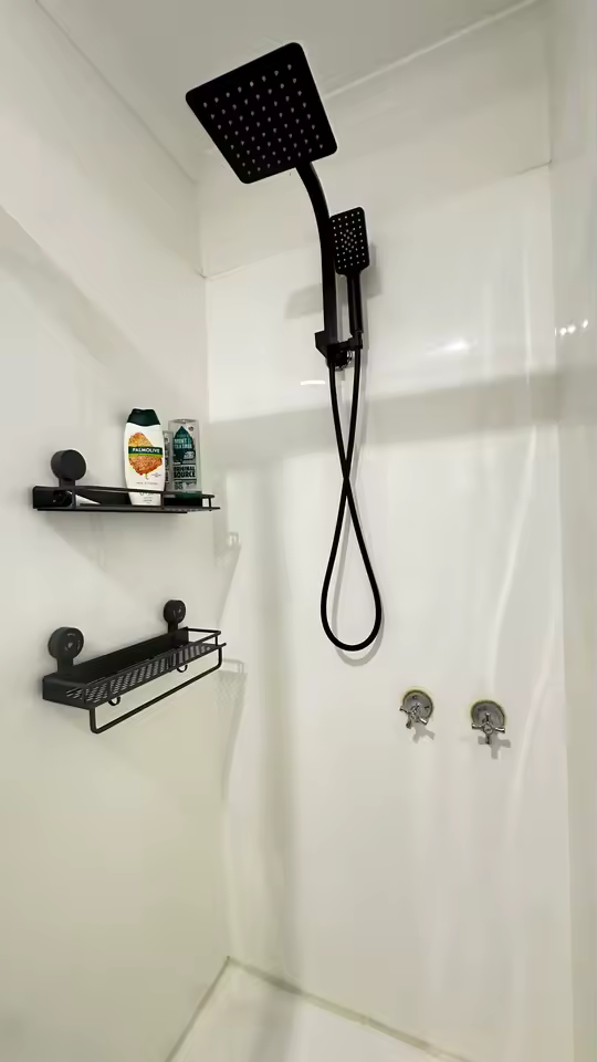 Two black GripNest shelves fitted beside a shower without drilling