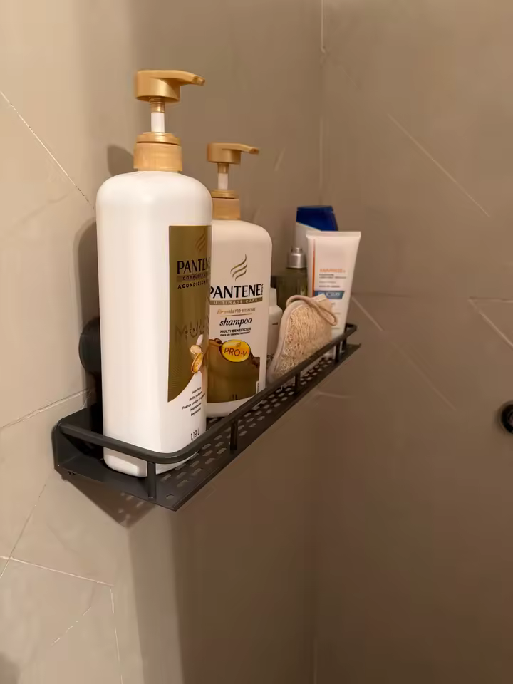 Black GripNest shelf holding full-size shampoo and skincare bottles